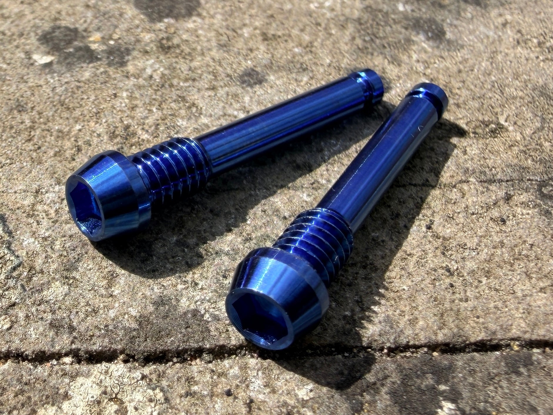 blue SRAM brake pad retention pins in CNC machined titanium