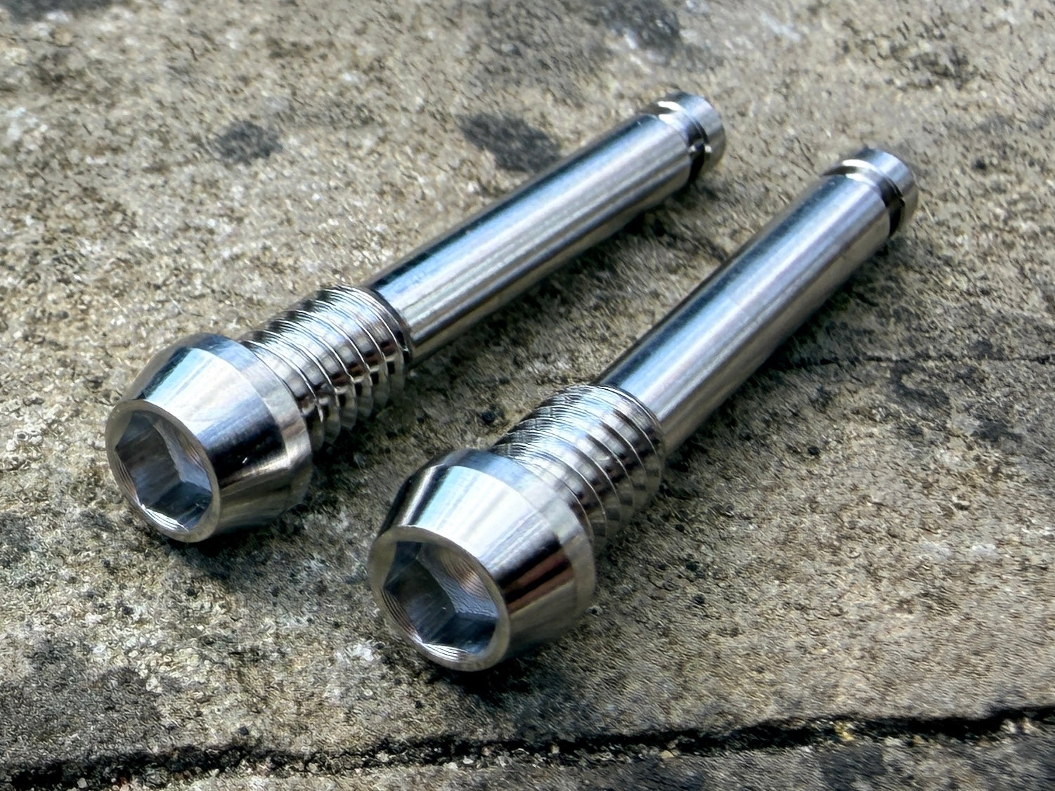 Silver SRAM brake pad retention pins in CNC machined titanium
