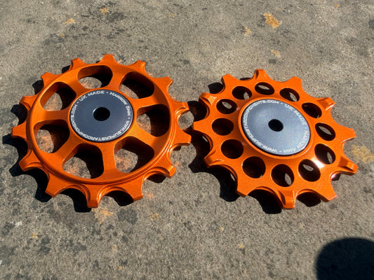 A pair of Orange jockey wheels with sealed bearings, designed for use with SRAM AXS rear derailleurs.
