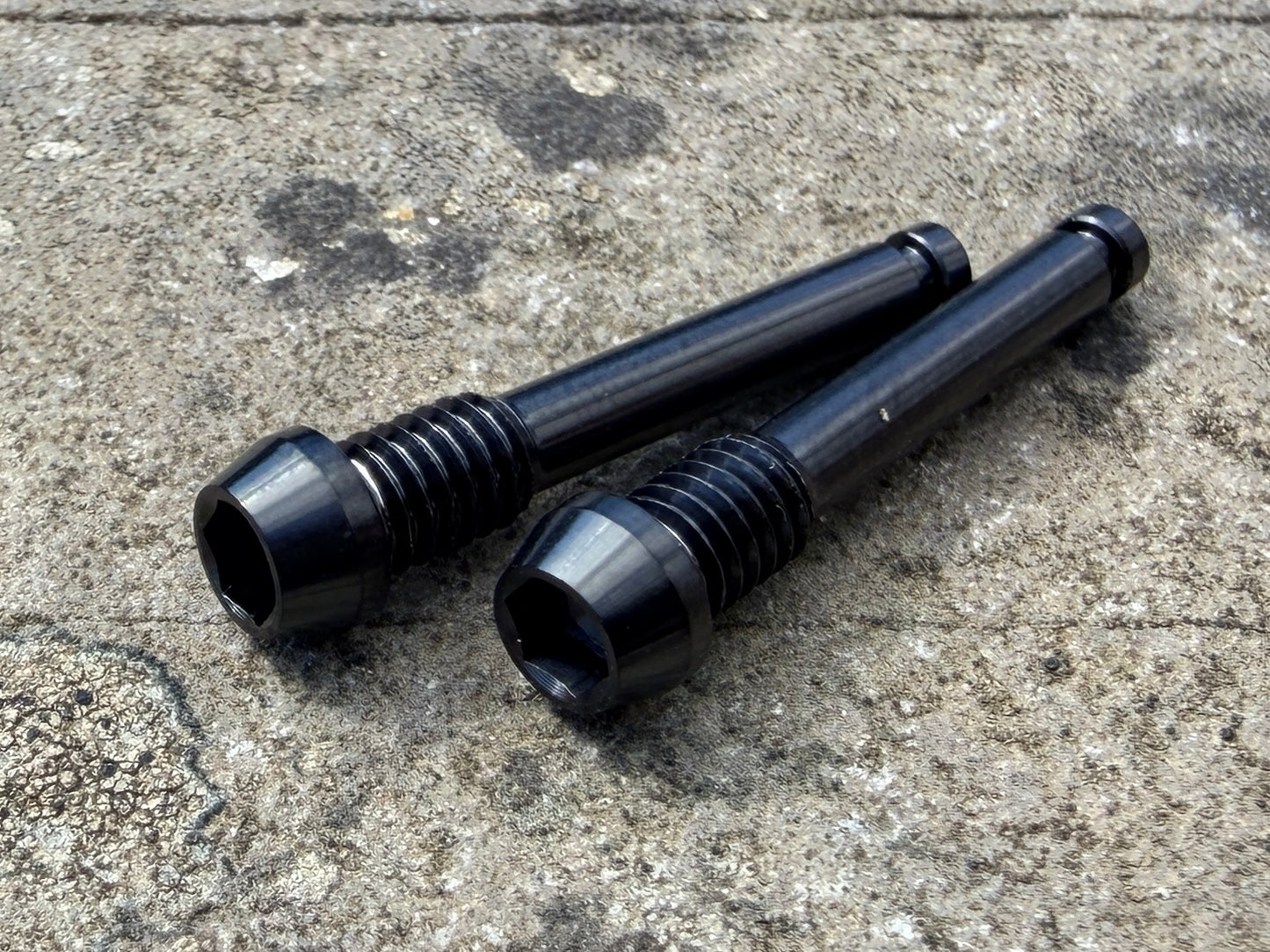 black SRAM brake pad retention pins in CNC machined titanium