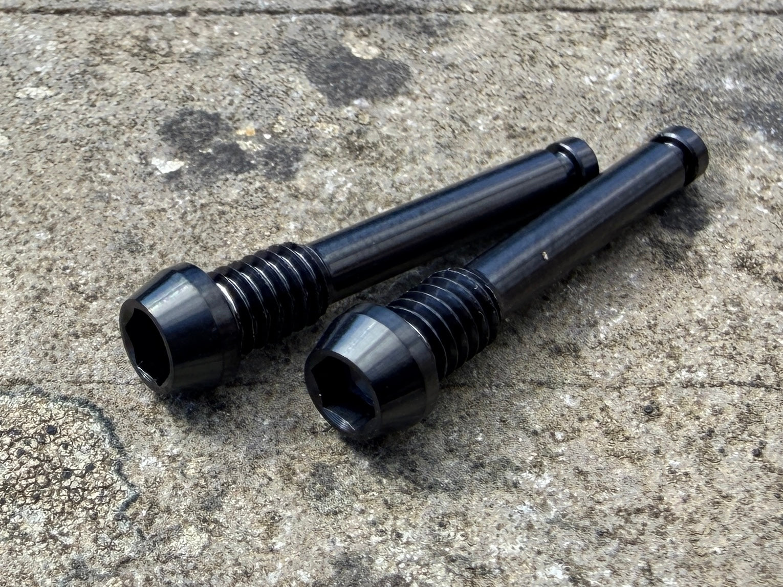 black SRAM brake pad retention pins in CNC machined titanium