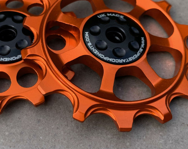 A pair of orange jockey wheels with visible bearing shields, designed for use with SRAM EAGLE rear derailleurs.